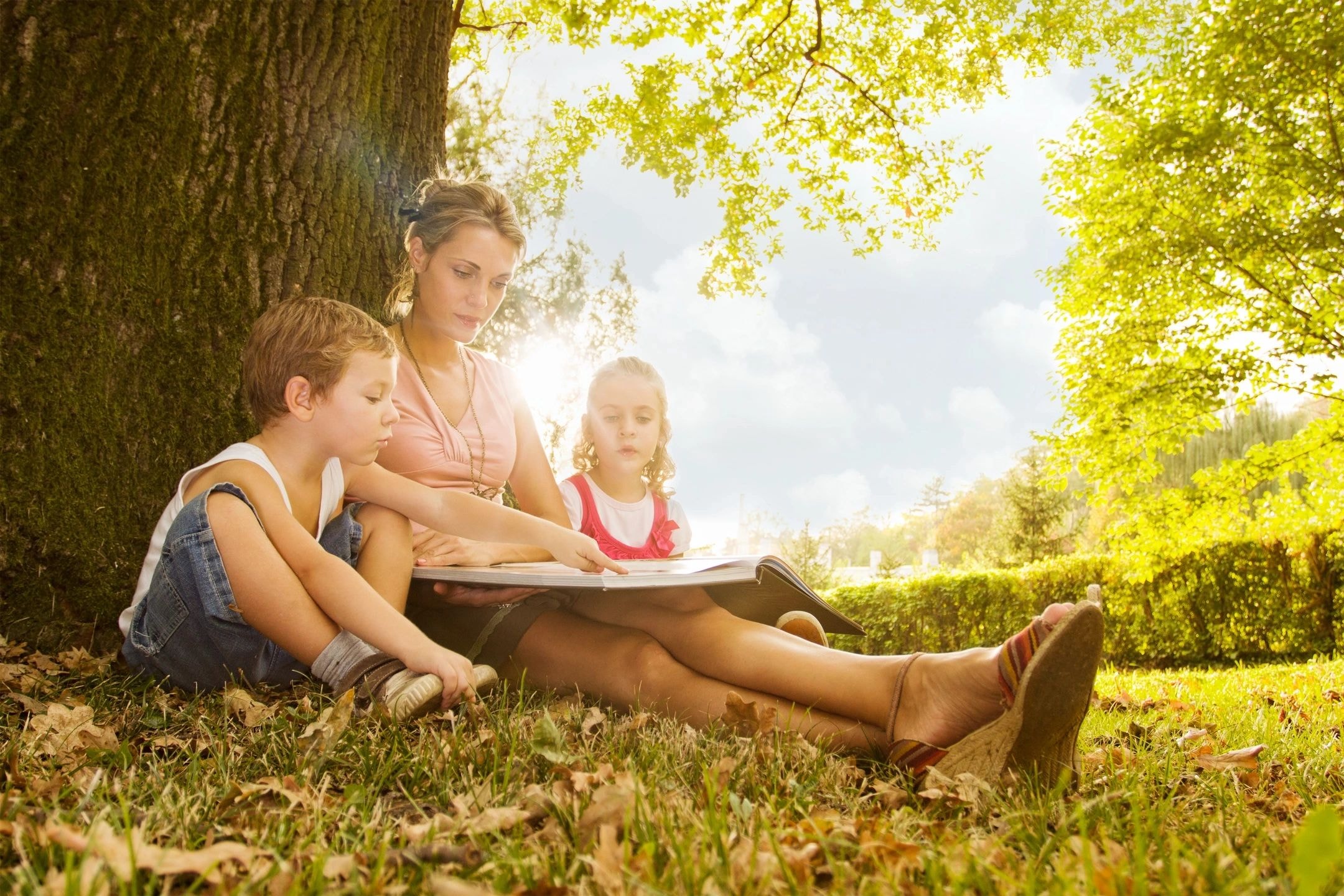 Mother reading to children outdoors